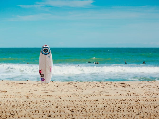 Surfboard on the sand at Jacó Beach with turquoise Pacific waves